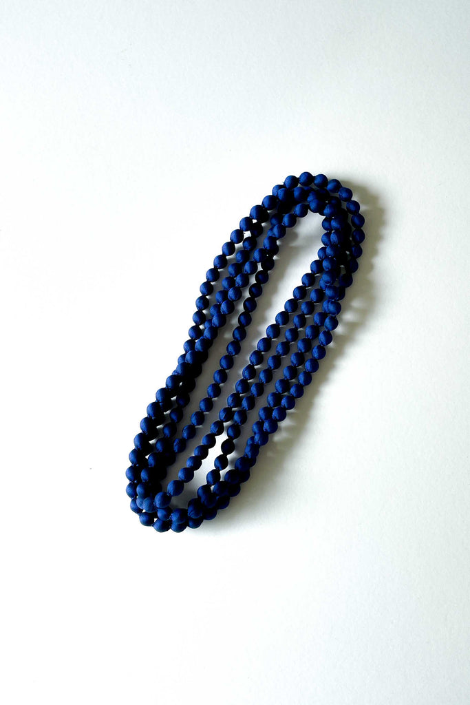 dark blue silk long strand woven necklace from tabitha foundation against white backdrop