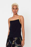 person with short blonde hair wearing gold binding silk camisole with metallic thread skirt against white backdrop