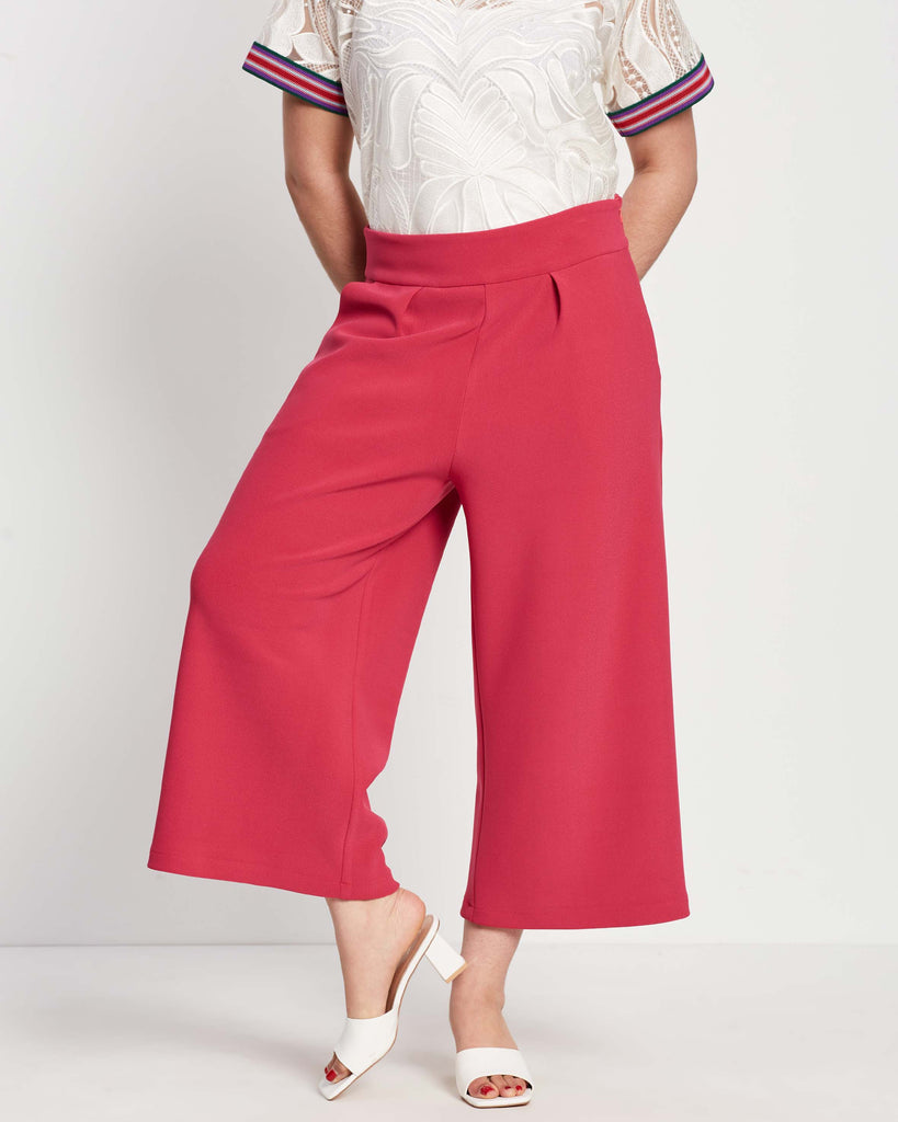 woman wearing pink crepe wide leg cropped culottes with pleat and white heeled slippers