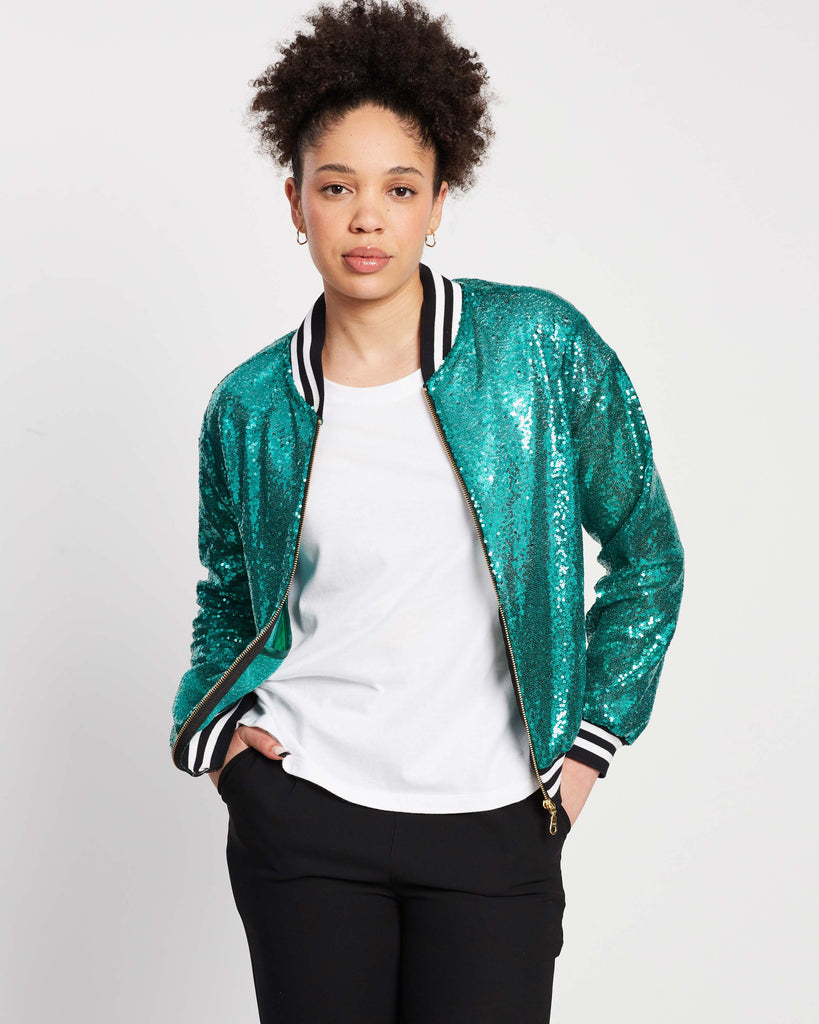 woman wearing teal disco bomber jacket with white t-shirt and black pants