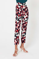 person wearing red white and black printed pants with white strap heels against a white backdrop