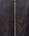 Close-up of a textured dark fabric with a zipper running vertically.
