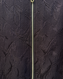 Close-up of a textured dark fabric with a zipper running vertically.