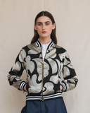 Person wearing a patterned bomber jacket against a plain background