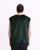 Person wearing a dark green fur vest on a white background