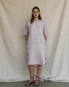 Woman wearing a light pink dress standing against a plain background