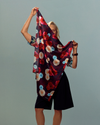 Model holding a burgundy floral square scarf. 