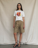 Model wearing an off-white t-shirt with a colourful graphic design and beige shorts against a plain background