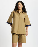 Woman wearing a Tan Short Quarter Sleeve Trench and shorts set with navy trim on a white background