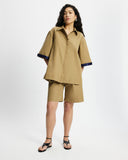 Woman wearing a Tan Short Quarter Sleeve Trench and shorts set with navy trim on a white background