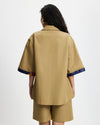 Woman wearing a Tan Short Quarter Sleeve Trench and shorts set with navy trim on a white background