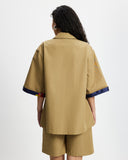 Woman wearing a Tan Short Quarter Sleeve Trench and shorts set with navy trim on a white background