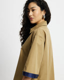 Woman wearing a Tan Short Quarter Sleeve Trench and shorts set with navy trim on a white background