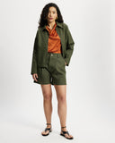 Woman wearing a Khaki Denim Workwear Jacket and shorts set with an orange shirt on a white background