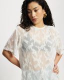Model wearing white sheer oversized top.