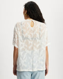 Model wearing white sheer oversized top with keyhole details