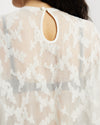 Model wearing white sheer oversized top with keyhole details