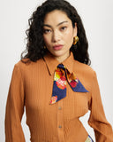 Model wears Silk Skinny Scarf in Nour tied in a bow around their neck