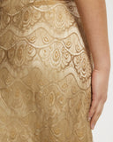 Close-up of a gold lace dress with intricate patterns on a white background