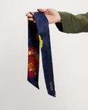 Navy blue floral scarf held by a model against a white background
