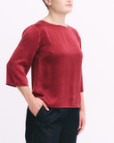 Person wearing a red top with 3/4 sleeves on a white background