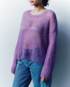 Person wearing a purple sweater and blue jeans against a plain background