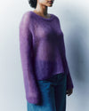 Person wearing a purple sweater and blue jeans against a plain background