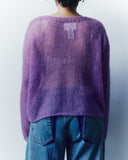 Person wearing a purple sweater and blue jeans against a plain background