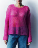 Person wearing a pink sweater and blue jeans against a white background