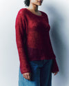 Person wearing a red sweater and blue pants against a plain background