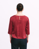 Person wearing a red blouse with a plain background