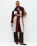 Woman wearing a color-blocked coat with a belt on a white background