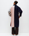Person wearing a long, multicolored coat with a white background