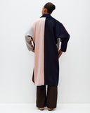 Person wearing a long, multicolored coat with a white background