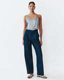 Woman wearing a gray tank top and dark blue pants on a white background