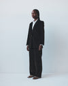 Person wearing a brown velvet suit and white shirt against a white background