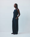 Woman wearing a dark blue vest and trousers against a white background