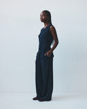 Woman wearing a dark blue vest and trousers against a white background