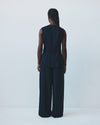 Person wearing a dark blue sleeveless top and wide-leg pants against a white background