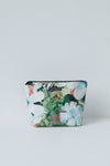 A small zippered cosmetic pouch with a watercolor floral print in green, white, and light blue, featuring a black zipper and a small black brand label.