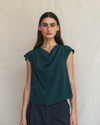 Woman wearing a green sleeveless top against a beige background