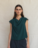 Woman wearing a green sleeveless top against a beige background