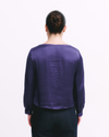 Person wearing a purple long-sleeve shirt on a white background