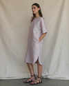 Woman wearing a light pink dress standing against a plain background