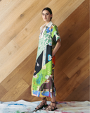 Woman wearing a colourful patchwork dress against a wooden wall.