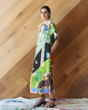 Model wearing a long patchwork dress against a wooden wall.
