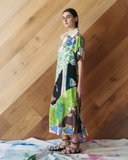 Model wearing a long patchwork dress against a wooden wall.