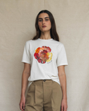 Person wearing an off-white t-shirt with a colorful floral design on a beige background