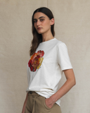 Woman wearing a white t-shirt with a colorful flower design on a beige background