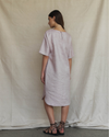 Woman wearing a light pink dress standing against a plain background